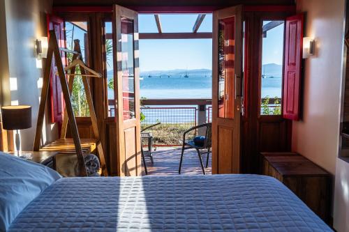 a bedroom with a bed and a view of the ocean at Pousada Mar de Dentro in Florianópolis