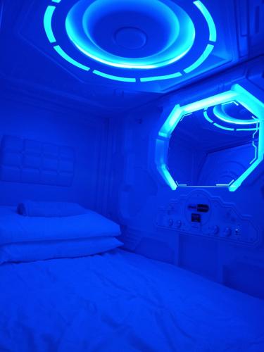 a room with a bed with a blue light at Galaxy Capsule Hotel near Hitech in Kulim