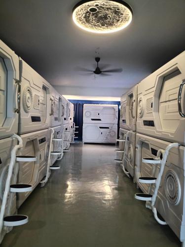 a laundry room with white washers and dryers at Galaxy Capsule Hotel near Hitech in Kulim