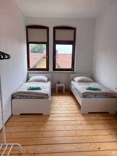 two beds in a room with two windows at Emmerstedt - Alte Schule in Helmstedt
