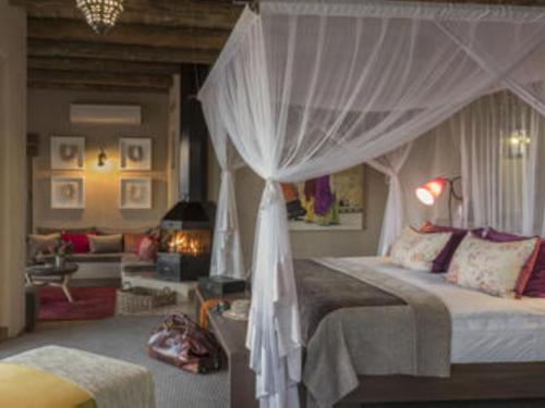 a bedroom with a canopy bed and a living room at Onguma The Fort in Namutoni Gate