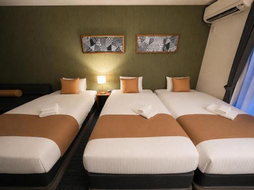 a group of three beds in a room at &zen Kyoto Gion in Kyoto