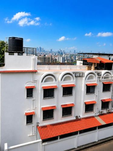 a white building with red roofs with a city in the background at MG Villa - A Boutique Stay in Navi Mumbai