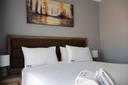 a bedroom with a white bed with a picture on the wall at The Ulysses Motel in Ga-Mothiba
