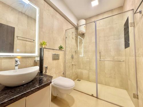 a bathroom with a toilet and a sink and a shower at 3BHK Elegant Duplex Villa with Pool Access in Assagao