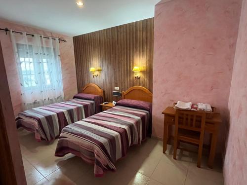 a room with two beds and a table with a telephone at Hotel Carvajal in Torrejón el Rubio