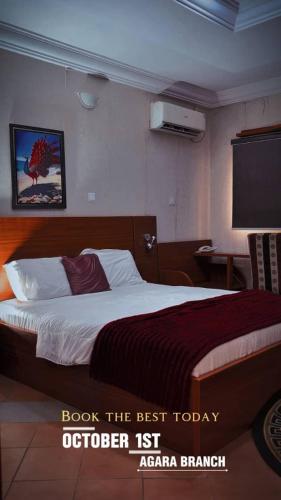 a bedroom with a bed with a red blanket and a television at October 1st Hotel in Ibadan