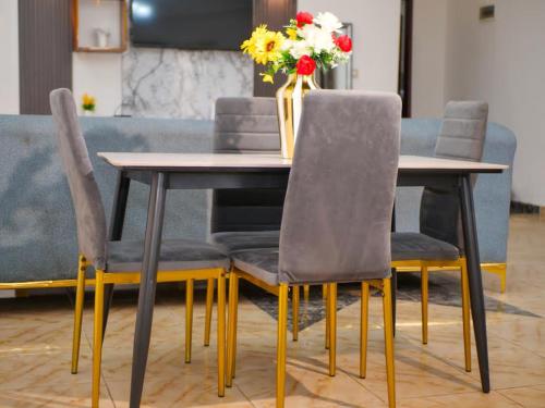 a dining room table with chairs and a vase of flowers at Maridel Home in Yaoundé