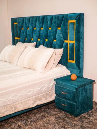 a bed with a blue headboard and a blue table at Maridel Home in Yaoundé