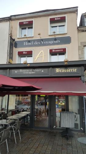 un restaurante con toldo rojo frente a un edificio en Hotel des Voyageurs, en Mayenne