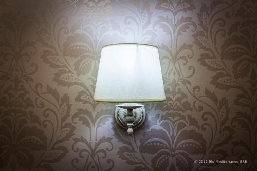 a lamp on a wall with a damask wallpaper at Blu Mediterraneo B&B in Messina