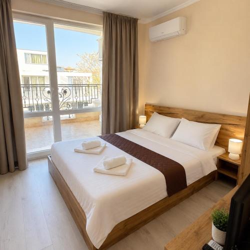 a bedroom with a large bed and a balcony at Bratanov Sveti Vlas Apartments in Sveti Vlas