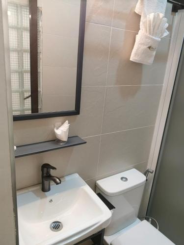 a bathroom with a toilet and a sink and a mirror at Bonds Hotel in Nairobi