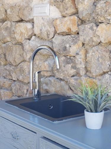 a kitchen sink with a stone wall at Apartman Zlatan in Drniš