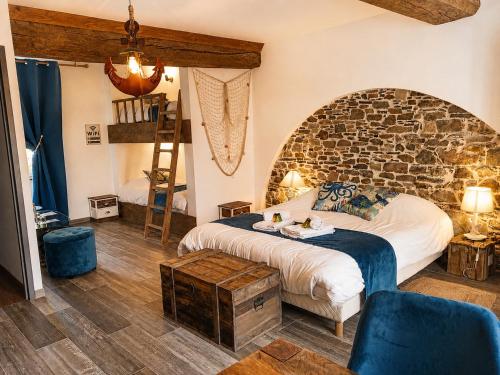 a bedroom with a bed and a stone wall at La Synchronicité - Chambres d'Hôtes in Vaudrimesnil