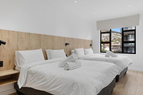 a bedroom with three beds with white sheets at Elsewhere in Cape Town