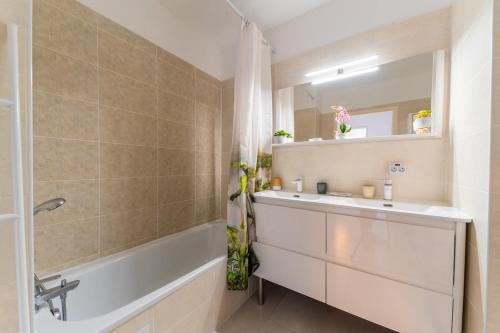 a bathroom with a sink and a tub and a mirror at Le Cocon Dracénois in Draguignan