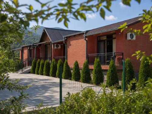 a red brick building with a fence and trees at Pesvebi Design Hotel and Cellar in Borjomi