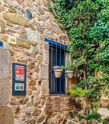 a window on a stone building with two potted plants at Casita de Mar in Tossa de Mar