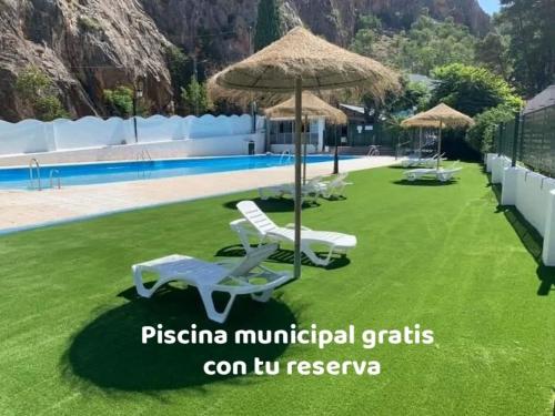 a lawn with chairs and umbrellas next to a pool at El Rincón de Ani in Torres
