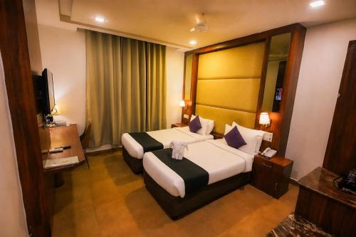 ein Hotelzimmer mit einem großen Bett und einem Fernseher in der Unterkunft Dazzling A Boutique Hotel in Agra
