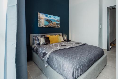 a bed in a bedroom with a blue wall at St Julians`s Urban Apartments in Is-Swieqi