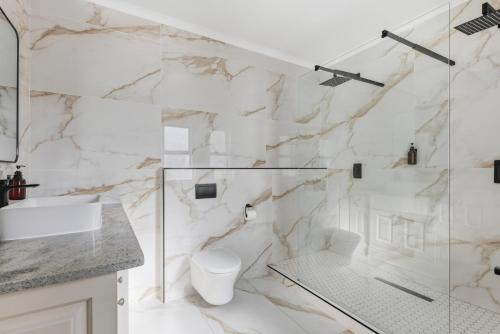 a white bathroom with a shower and a toilet at Elsewhere in Cape Town
