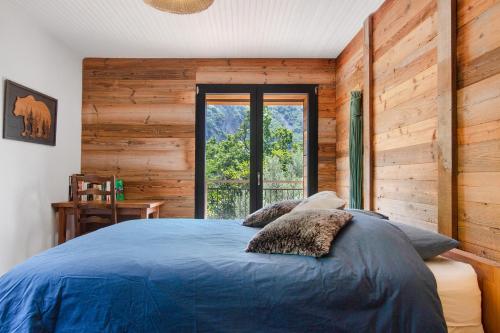 a bedroom with a blue bed and a window at Gite Les Grillons in Belvédère