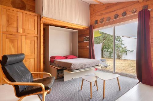 a bedroom with a bed and a chair and a window at Chalet Studio Athome in Bouhet
