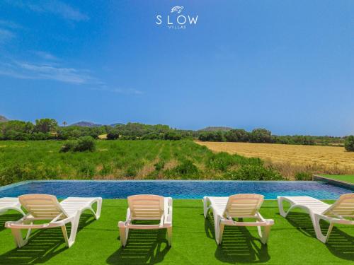 a group of lawn chairs sitting next to a pool at Villa Son Bennasar by Slow Villas in Felanitx