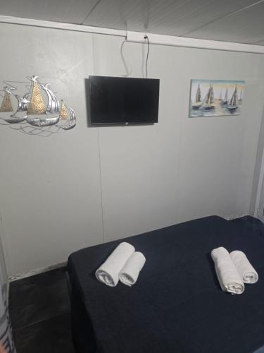 a bedroom with a bed with slippers and a flat screen tv at Krikonis Apartments Leptokarya in Leptokarya