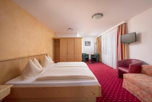 a hotel room with a bed and a chair at Hotel Fischer in Sankt Johann in Tirol