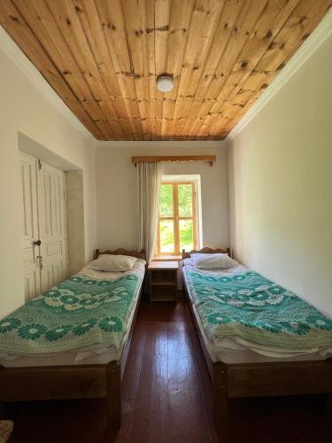 two beds sitting in a room with a window at Otisha Guesthouse in Tsaldashi