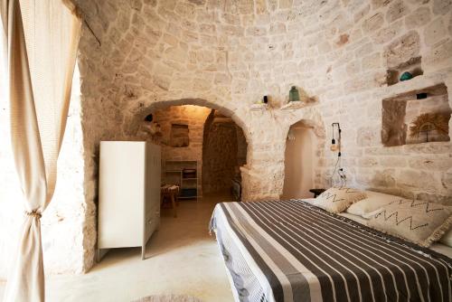 a bedroom with a bed in a stone wall at Trullo KAVA - Ceglie Messapica in Ceglie Messapica