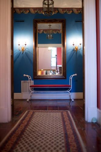 a mirror in a blue room with a bench in front of it at Barksdale House Inn in Charleston