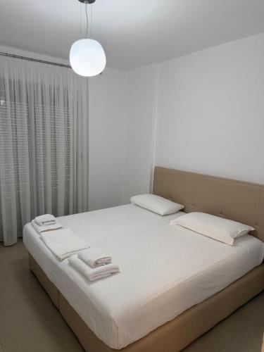 a white bedroom with a large bed with white sheets at Miramare Aparthotel in Sarandë