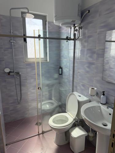 a bathroom with a shower and a toilet and a sink at Miramare Aparthotel in Sarandë