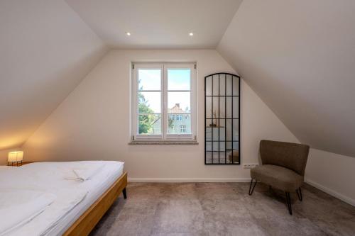 a bedroom with a bed and a chair and a window at Traumgarten Traumzeit in Prerow