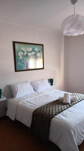 a bedroom with a large white bed with a painting on the wall at Casa dos avós in Redondela