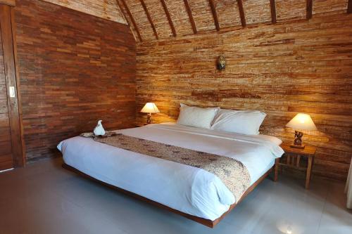 a bedroom with a large bed in a wooden wall at Maruti Beach Villas in Nusa Penida