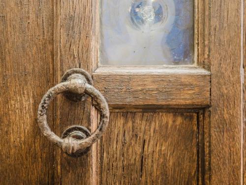 an old wooden door with a rusty ring on it at La Casa 1832 Boutique in Sanlúcar de Barrameda