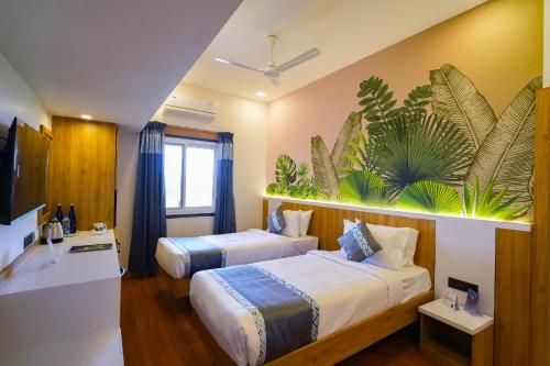a hotel room with two beds with plants on the wall at MGM Vailankanni in Velankanni