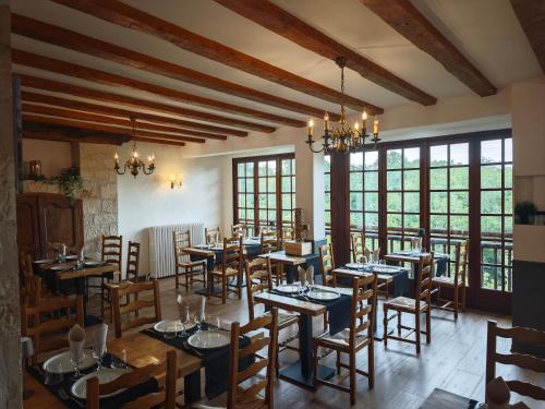 a restaurant with tables and chairs in a room with windows at Le Fenelon in Carennac