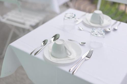 a white table with silverware on a white table cloth at Gruppo Luxe Domus Vigevano in Vigevano