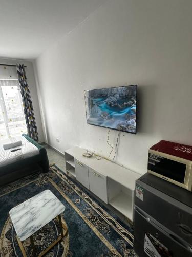 a living room with a couch and a tv on the wall at Tsavo in Nairobi