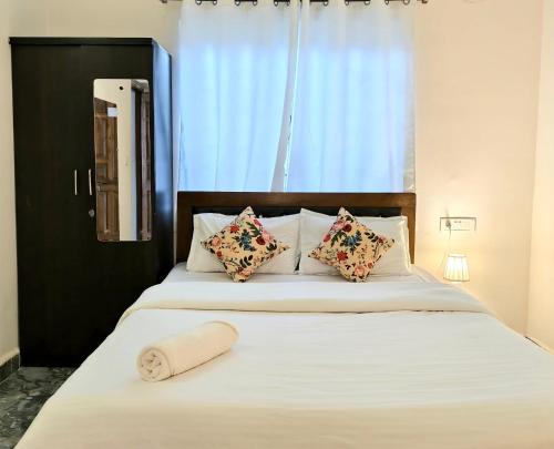 a bedroom with a large white bed with pillows at Daffodil in Anjuna