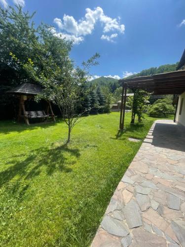 a green yard with a tree and a gazebo at Gama House & Garden with restaurant in Vişeu de Sus