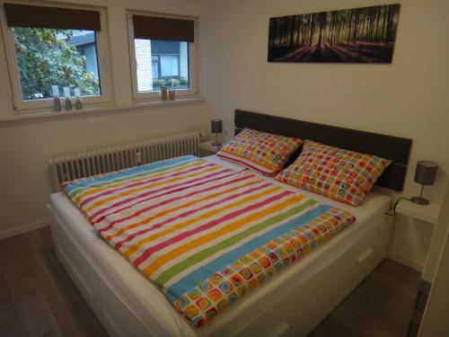 ハーネンクレー・ボックスヴィーゼにあるFewo Andresen Hahnenkleeのベッド1台(カラフルな毛布、枕2つ付)
