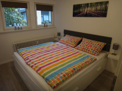 a bed with a colorful blanket and two pillows on it at Fewo Andresen Hahnenklee in Hahnenklee-Bockswiese