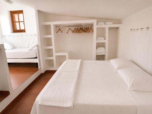 a white bedroom with a white bed and a chair at Perla Marina Tropea in Parghelia